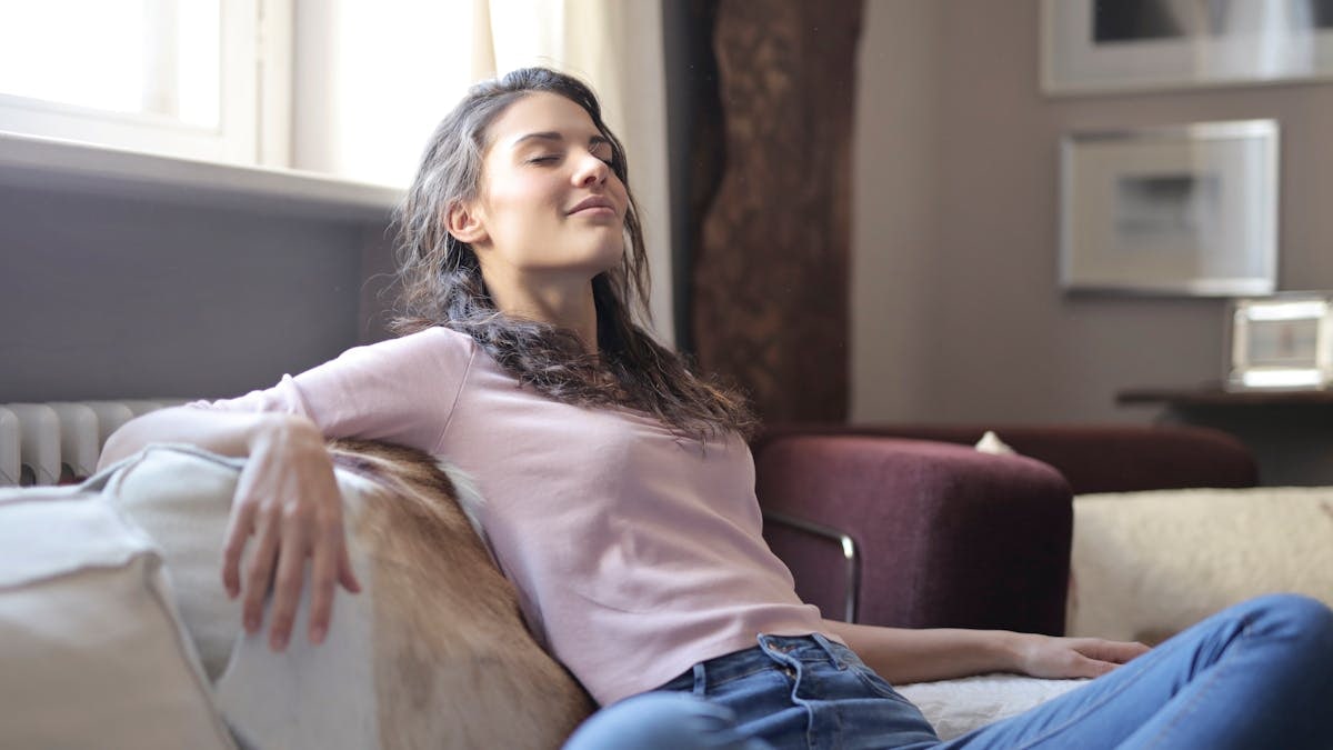 Woman relaxing on a couch in a cozy living room, embodying tranquility and comfort.